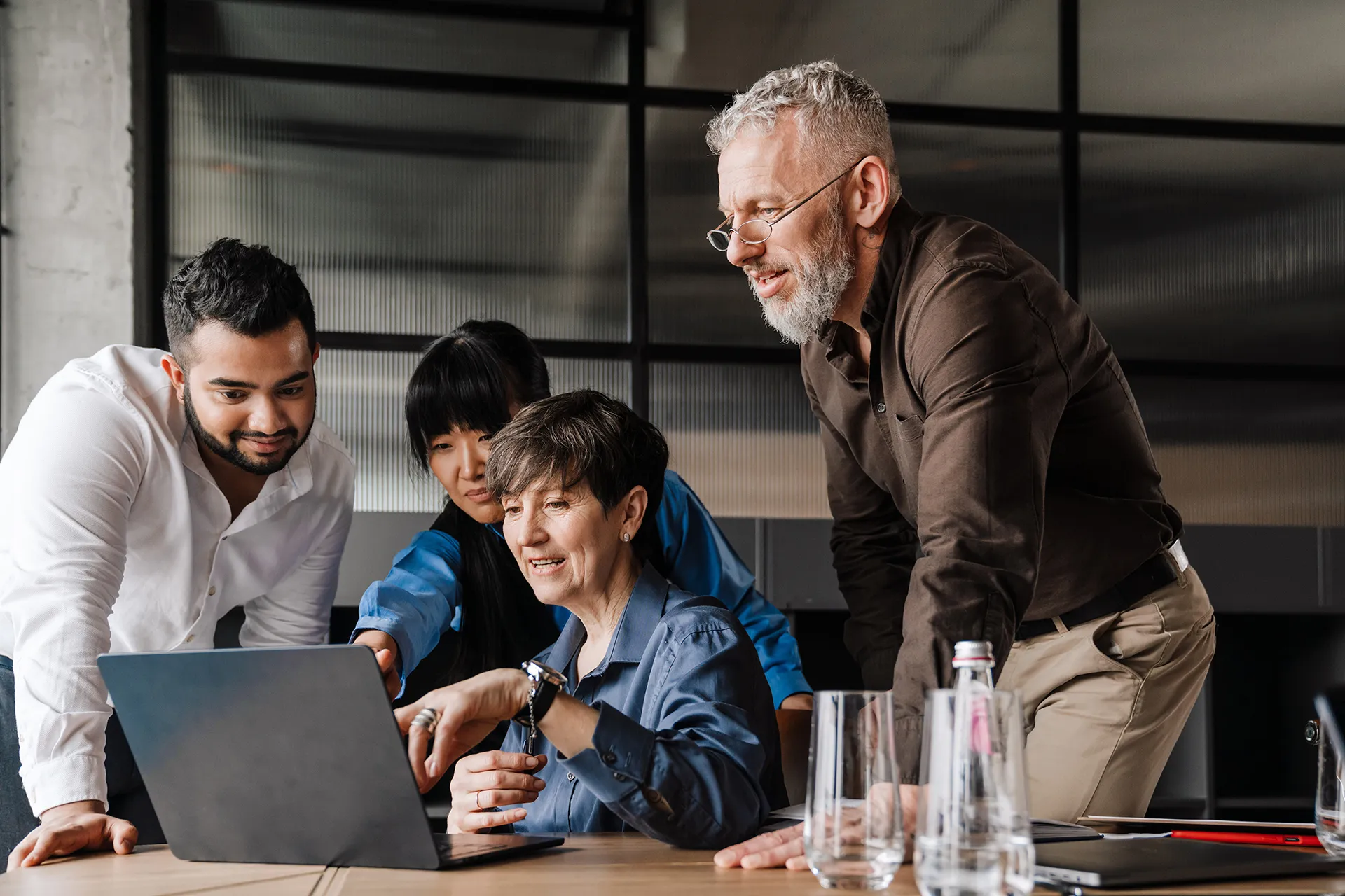 Erfahrene Fachkräfte und junges Team besprechen sich am Laptop – SAP-Anwendungsberatung durch Experten im Ruhestand über Sentaris